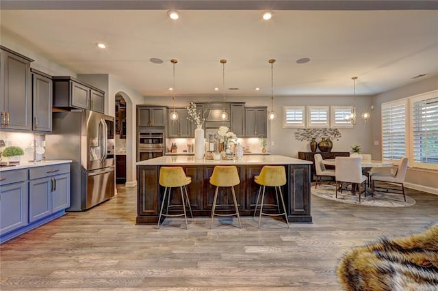 13 Clearwater Ct, Hoschton, GA 30548 - kitchen with stainless steel appliances, light wood-style floors, a chandelier, light countertops, and arched walkways