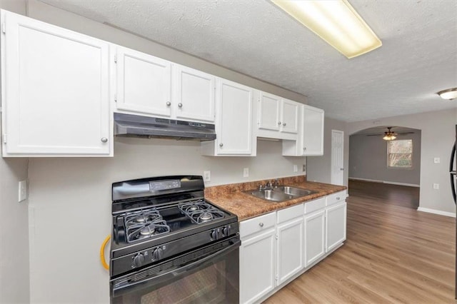 kitchen with a sink, under cabinet range hood, black range with gas stovetop, white cabinetry, and light wood-type flooring