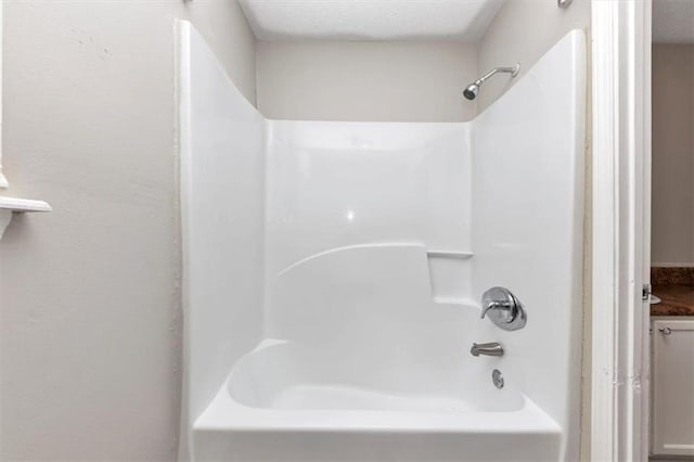 full bath featuring a textured ceiling and washtub / shower combination