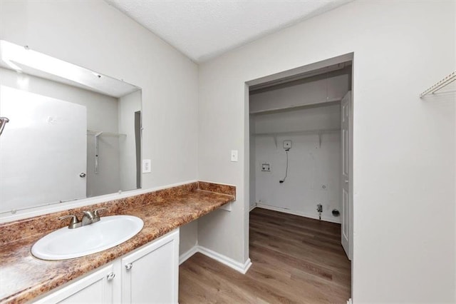 bathroom featuring a textured ceiling, vanity, baseboards, and wood finished floors