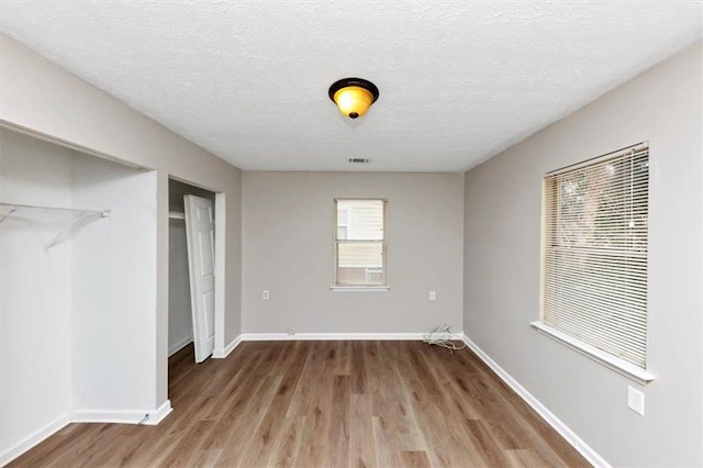 unfurnished bedroom with visible vents, wood finished floors, baseboards, and a textured ceiling