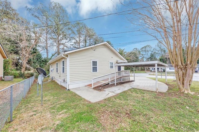 back of house with a carport, a yard, and fence