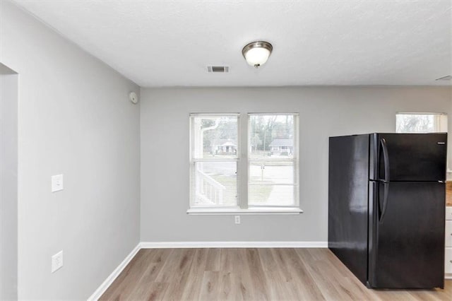 kitchen featuring visible vents, freestanding refrigerator, baseboards, and wood finished floors