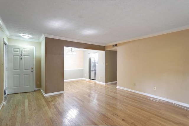 unfurnished room featuring light wood-type flooring, a textured ceiling, a notable chandelier, and crown molding