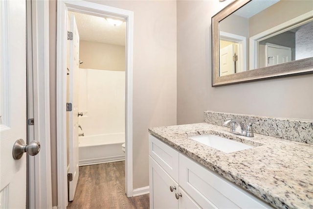 full bathroom featuring wood-type flooring, a textured ceiling, toilet, shower / tub combination, and vanity