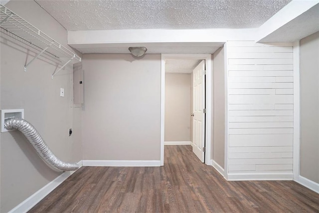 basement with a textured ceiling, electric panel, and dark wood-type flooring