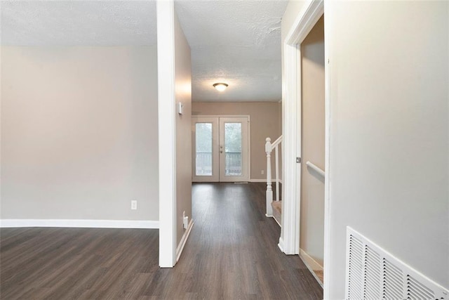 hall featuring french doors, dark hardwood / wood-style flooring, and a textured ceiling