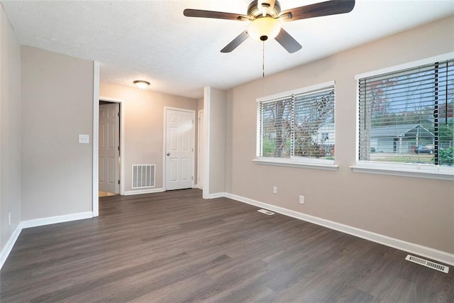 empty room with dark hardwood / wood-style floors, ceiling fan, and a textured ceiling