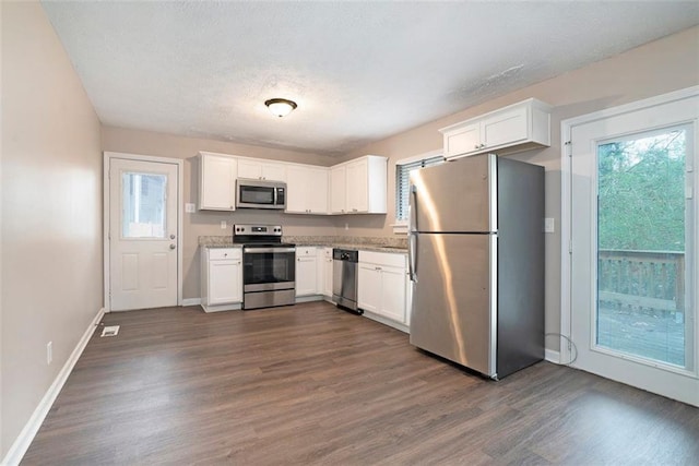 kitchen with light stone countertops, white cabinetry, dark hardwood / wood-style flooring, and stainless steel appliances