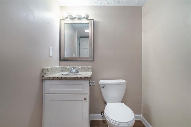 bathroom featuring vanity, a textured ceiling, and toilet