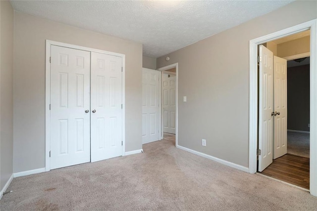 unfurnished bedroom featuring light colored carpet, a textured ceiling, and a closet