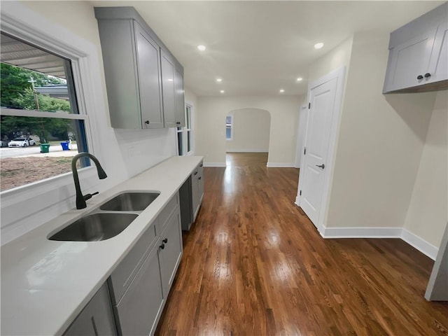 1955 S Columbia Pl, Decatur, GA 30032 - kitchen with gray cabinets, a sink, dark wood finished floors, arched walkways, and baseboards