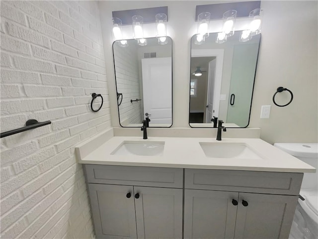 1955 S Columbia Pl, Decatur, GA 30032 - full bathroom featuring double vanity, toilet, brick wall, and a sink