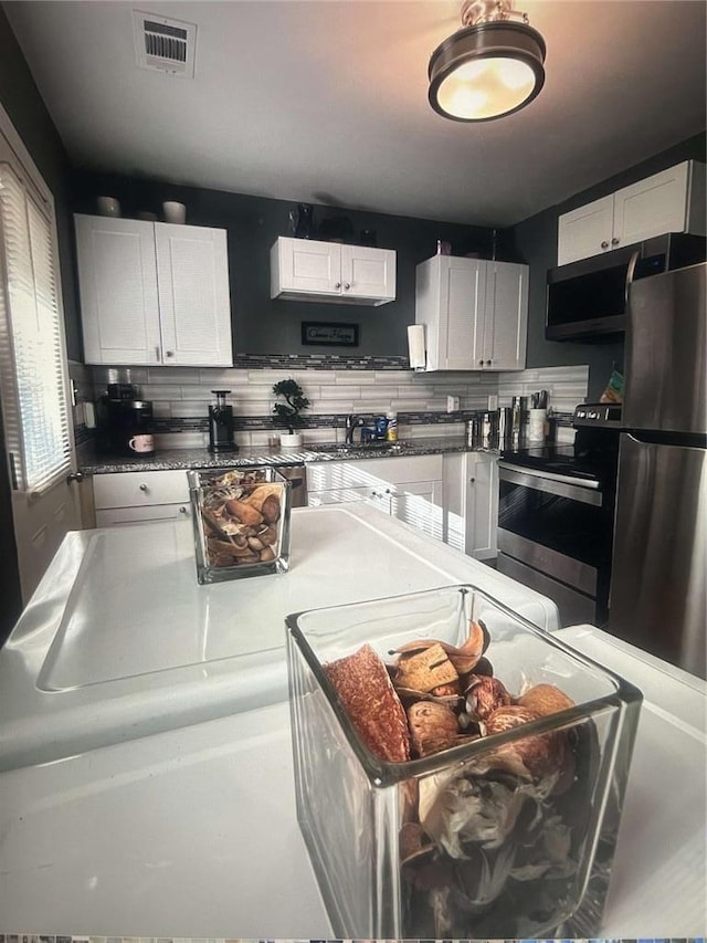 1132 SE Oak Knoll Ter SE, Atlanta, GA 30315 - kitchen featuring appliances with stainless steel finishes, white cabinetry, and decorative backsplash