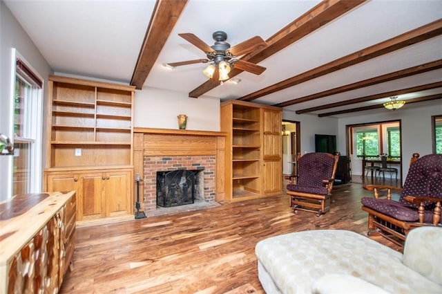 3187 Oak Grove Church Rd, Carrollton, GA 30117 - living area with beamed ceiling, wood finished floors, a ceiling fan, and a brick fireplace