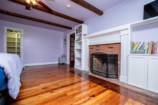3187 Oak Grove Church Rd, Carrollton, GA 30117 - unfurnished living room featuring beam ceiling, wood finished floors, a fireplace, a ceiling fan, and baseboards