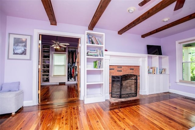 3187 Oak Grove Church Rd, Carrollton, GA 30117 - unfurnished living room with a ceiling fan, wood finished floors, a fireplace, beamed ceiling, and baseboards