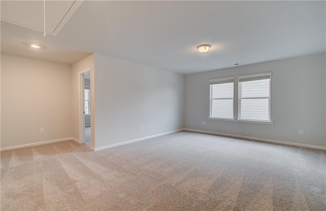 spare room with light carpet, baseboards, and attic access