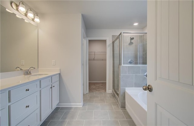 bathroom featuring baseboards, a walk in closet, vanity, a stall shower, and tile patterned flooring