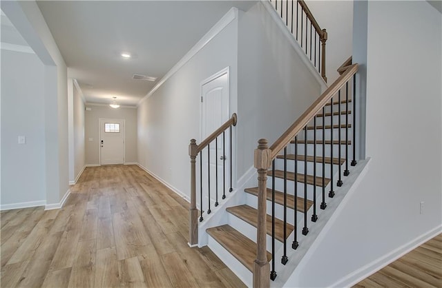 foyer featuring visible vents, crown molding, baseboards, stairway, and light wood-type flooring