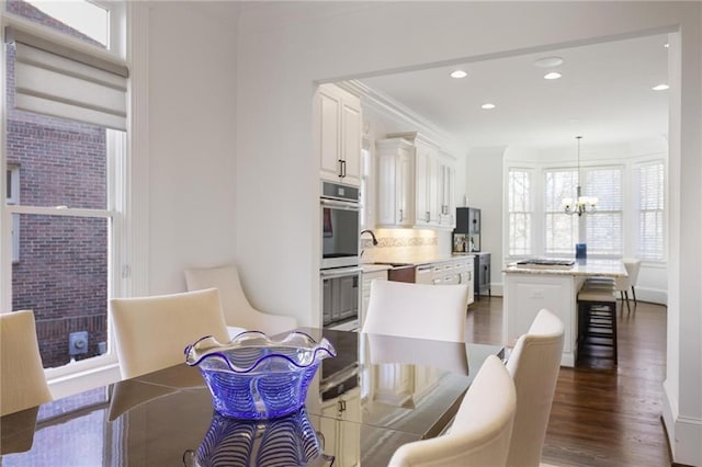 dining area with crown molding, a notable chandelier, sink, and dark hardwood / wood-style floors