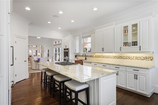 kitchen featuring light stone counters, a breakfast bar, a kitchen island, and white cabinets