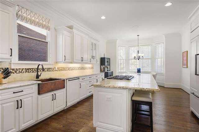 kitchen featuring white cabinetry, sink, hanging light fixtures, a center island, and crown molding