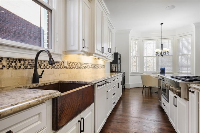 kitchen with white cabinetry, decorative light fixtures, a notable chandelier, light stone countertops, and decorative backsplash