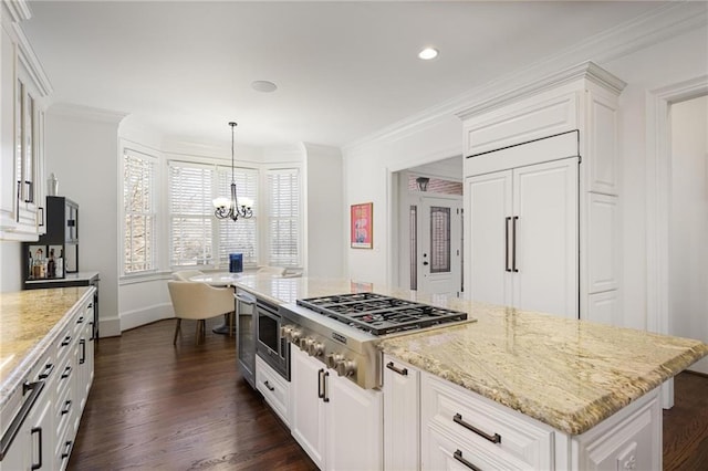 kitchen featuring white cabinetry, stainless steel appliances, decorative light fixtures, and a center island