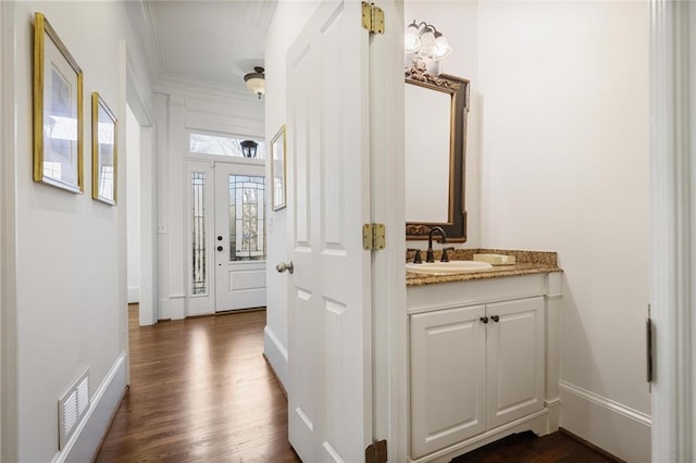 hallway with crown molding, dark wood-type flooring, and sink