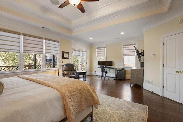 bedroom with ornamental molding, a tray ceiling, dark hardwood / wood-style flooring, and multiple windows