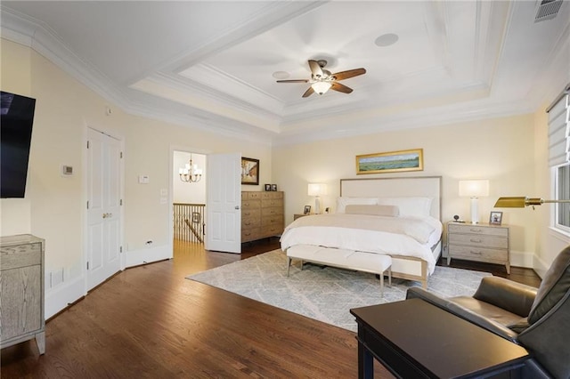 bedroom featuring dark wood-type flooring, ornamental molding, a tray ceiling, and ceiling fan with notable chandelier