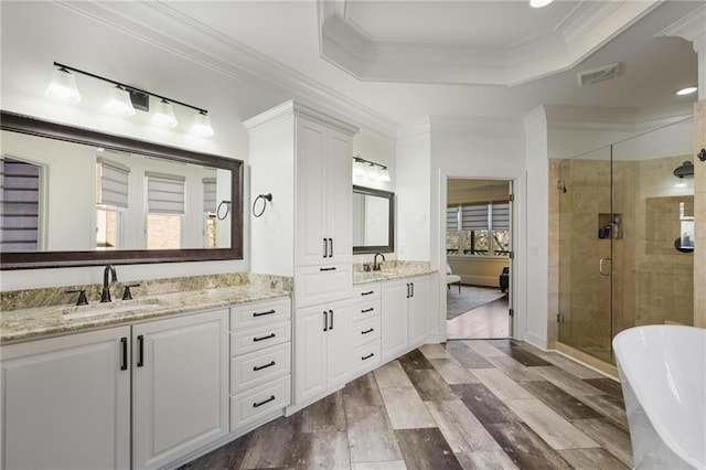 bathroom with hardwood / wood-style flooring, vanity, a tray ceiling, ornamental molding, and independent shower and bath