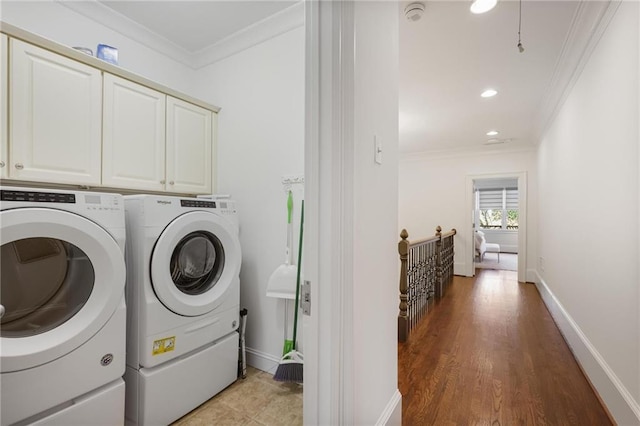 laundry area featuring cabinets, wood-type flooring, ornamental molding, and washer and dryer