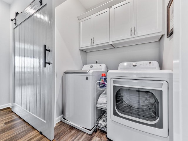 washroom featuring washing machine and clothes dryer, a barn door, cabinets, and dark wood-type flooring