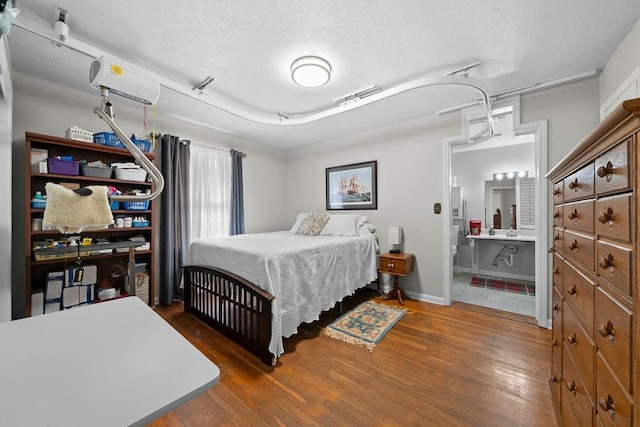 bedroom featuring a textured ceiling, dark hardwood / wood-style floors, and connected bathroom