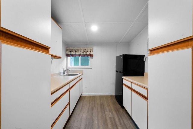 kitchen featuring sink, black fridge, white cabinets, and hardwood / wood-style flooring