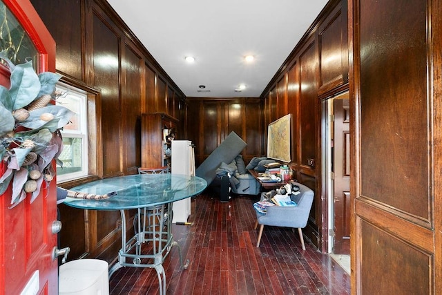 kitchen with wood walls, dark hardwood / wood-style flooring, a breakfast bar, and ornamental molding