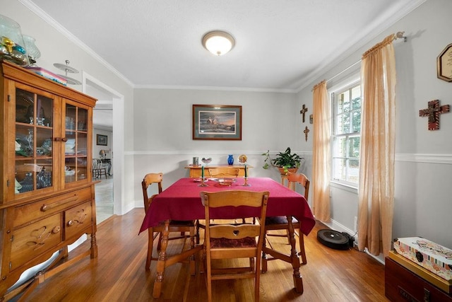 dining space with wood-type flooring and ornamental molding