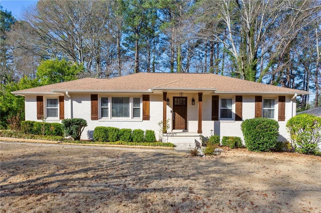 ranch-style house featuring brick siding and roof with shingles
