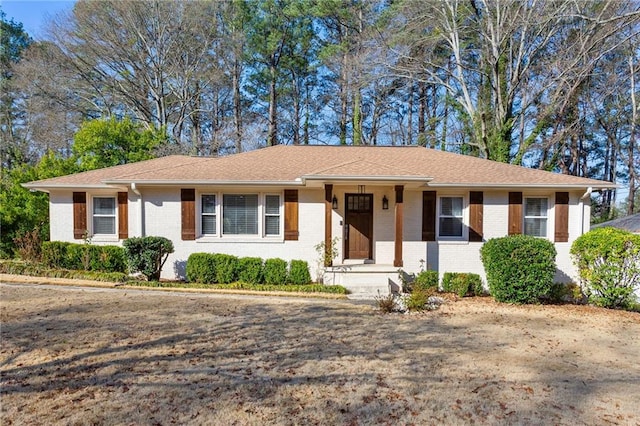 ranch-style house featuring brick siding and roof with shingles