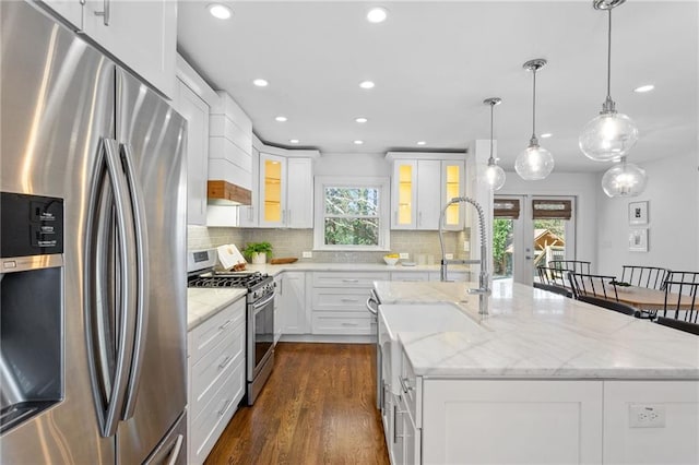 kitchen with dark wood finished floors, an island with sink, decorative backsplash, french doors, and stainless steel appliances