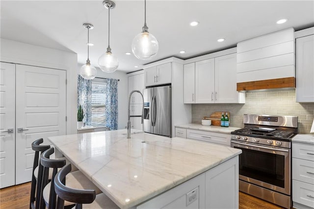 kitchen with tasteful backsplash, an island with sink, custom range hood, appliances with stainless steel finishes, and white cabinets