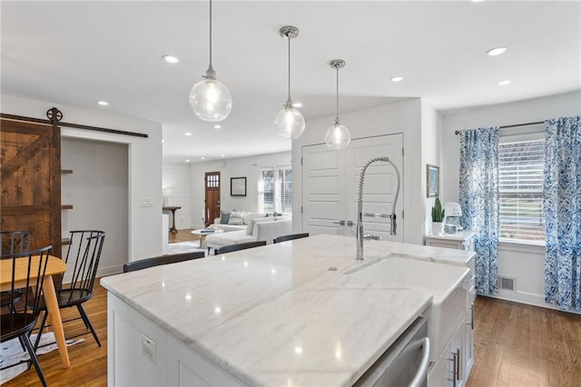 kitchen featuring a barn door, wood finished floors, and white cabinets