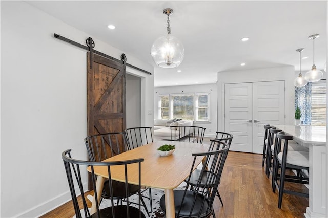 dining room with recessed lighting, a barn door, baseboards, and dark wood finished floors