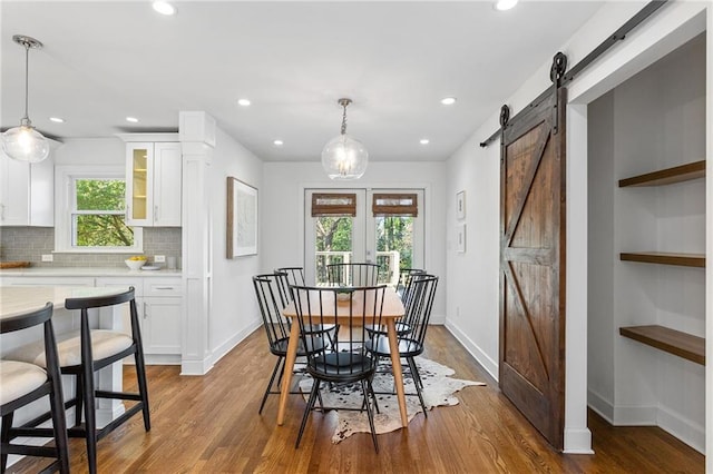 dining area featuring a barn door, recessed lighting, wood finished floors, and baseboards