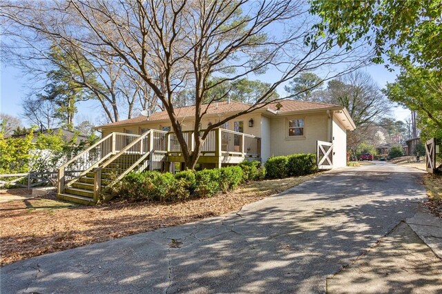 view of side of home with aphalt driveway, stairs, and brick siding