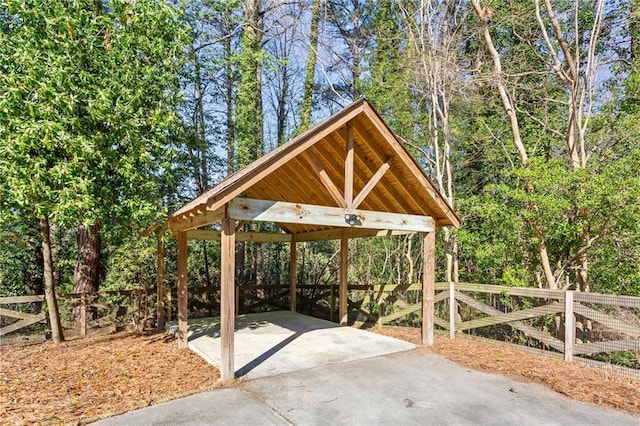 view of patio with a detached carport, fence, and driveway