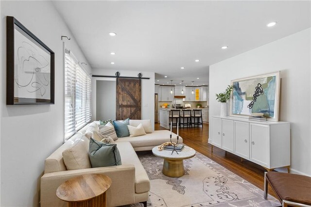 living area featuring a barn door, recessed lighting, and dark wood-style flooring