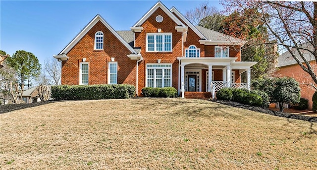 view of front facade featuring a front yard, a porch, and brick siding